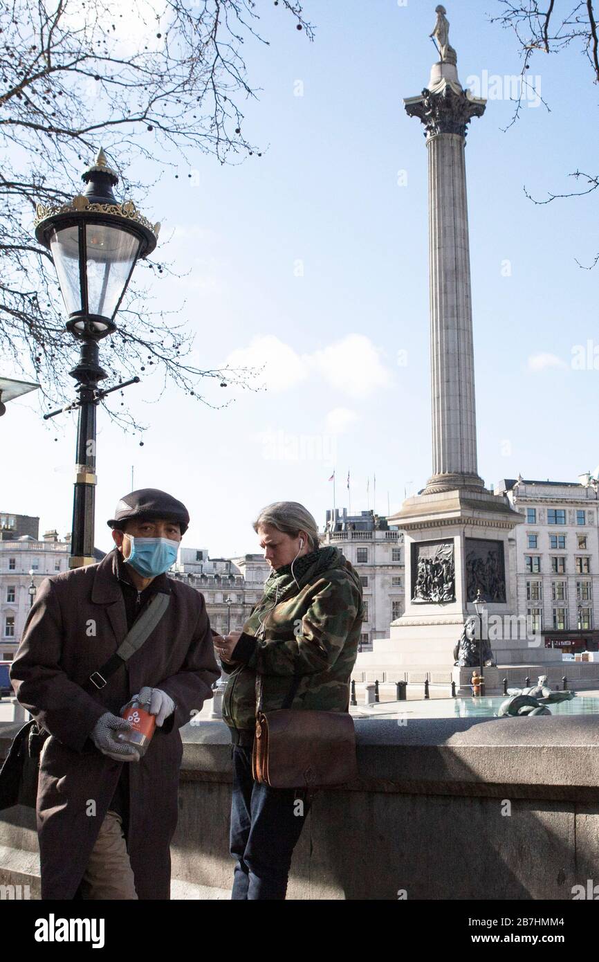 A man wearing a mask walks through Trafalgar Square, London, as people begin another week as the ongoing spread of Coronvirus (COVID-19) effects the Stock Photo
