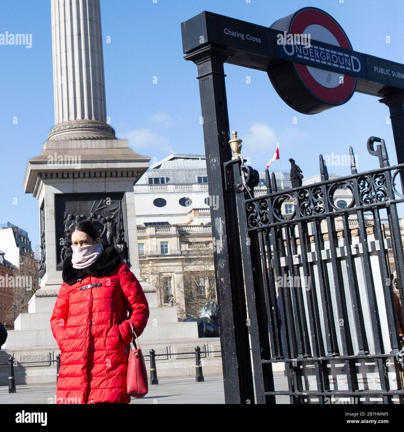 A woman wearing a mask walks through Trafalgar Square, London, as people begin another week as the ongoing spread of Coronvirus (COVID-19) effects the Stock Photo