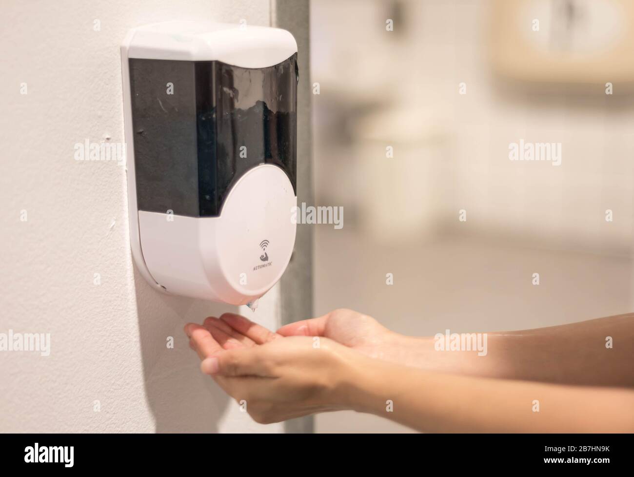 Female hand use the automatic alcohol dispenser in front of the public area , Coronavirus infection or COVID-19 outbreak prevention all around the wor Stock Photo