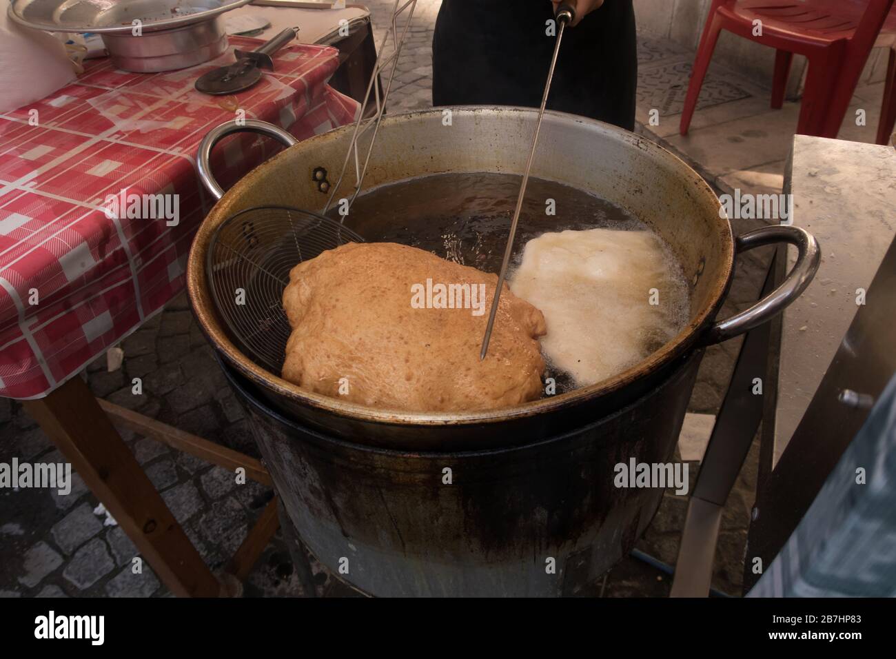 A fried pizza being prepared in boiling oil in a street of naples Stock Photo