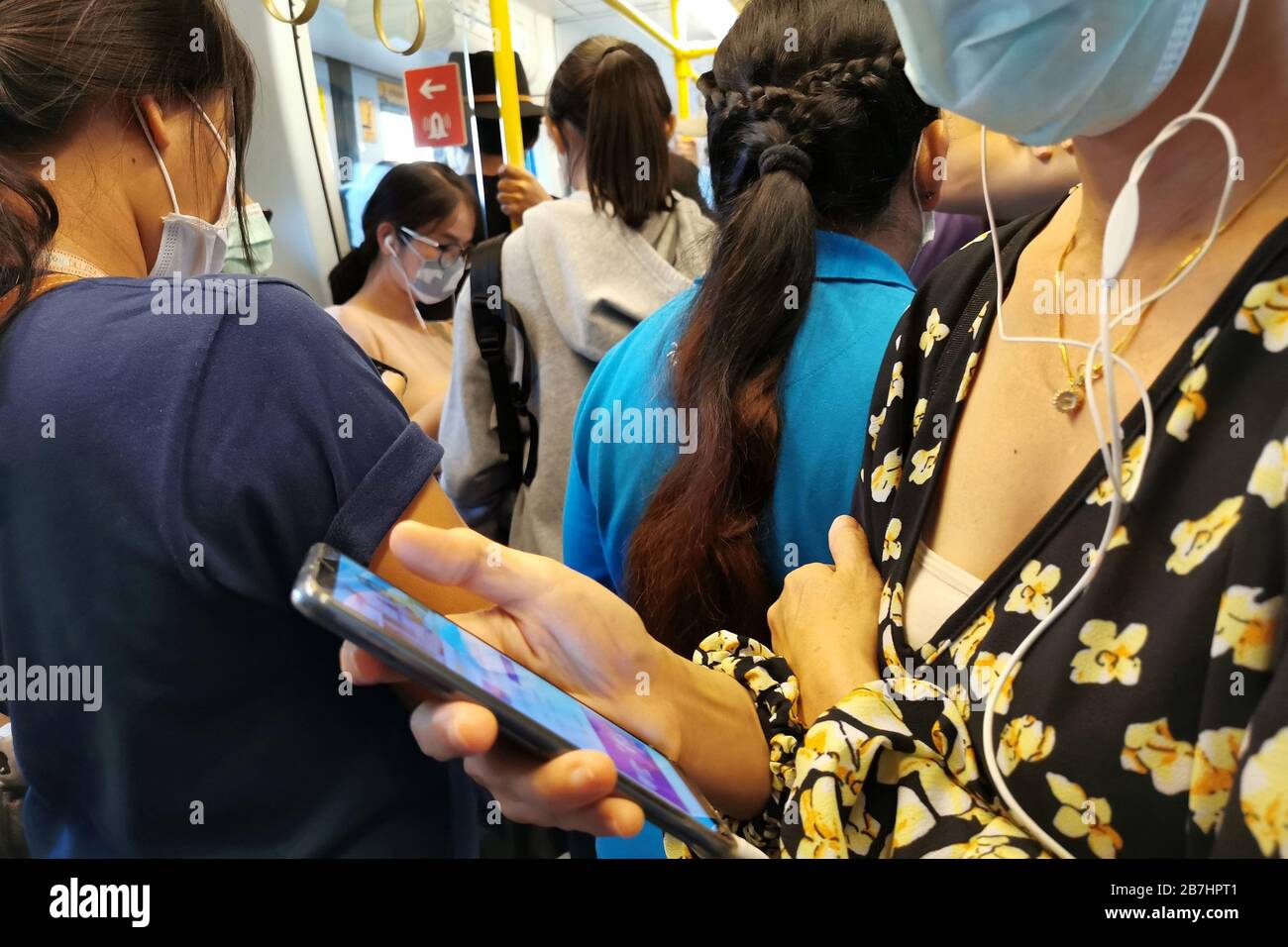 Bangkok, Thailand - March 14, 2020 : asian passengers in sky train public transport wearing hygiene face mask going to work and checking pandemic news Stock Photo