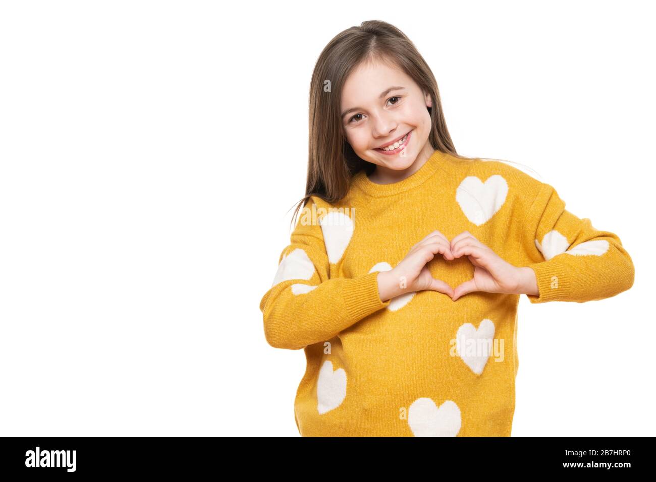 Studio portrait of a little girl on white background making a heart gesture with her hands. Fostering a child, humanitarian aid, cooperation, donation Stock Photo