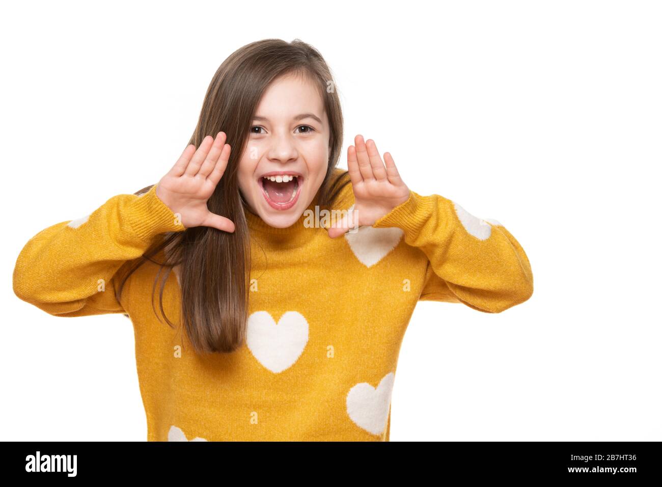 Studio portrait of an adorable young girl screaming with excitement, isolated on white backgroud. Human emotions and facial expressions concept. Stock Photo