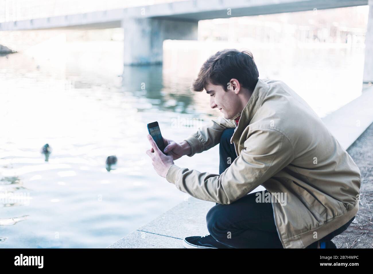 young male taking photos outdoors by mobile phone Stock Photo