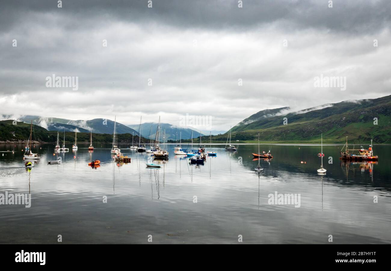 Boats moored on Loch Broom, Ullapool, Scotland. A view from Ullapool over the calm lake in the Scottish Highlands with overcast low cloud coverage. Stock Photo