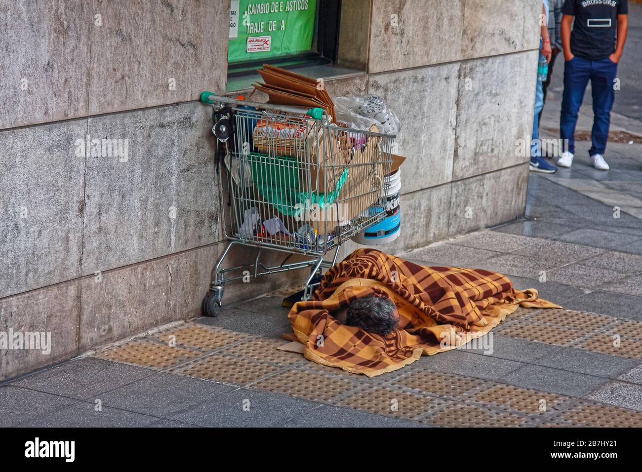 homeless person; poverty; shopping cart; possessions, sleeping; street corner; blanket; South America; Buenos Aires; Argentina; summer Stock Photo