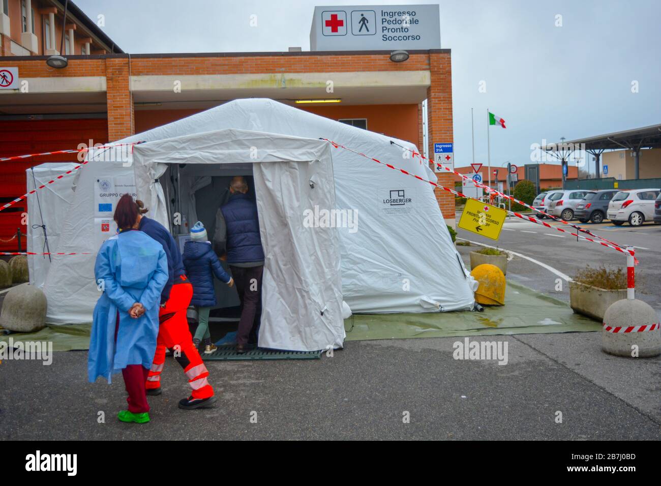 Triage outside the hospital due to coronavirus pandemic. Temporary tent set outside with paramedics and nurses to measure body temperature and contain Stock Photo