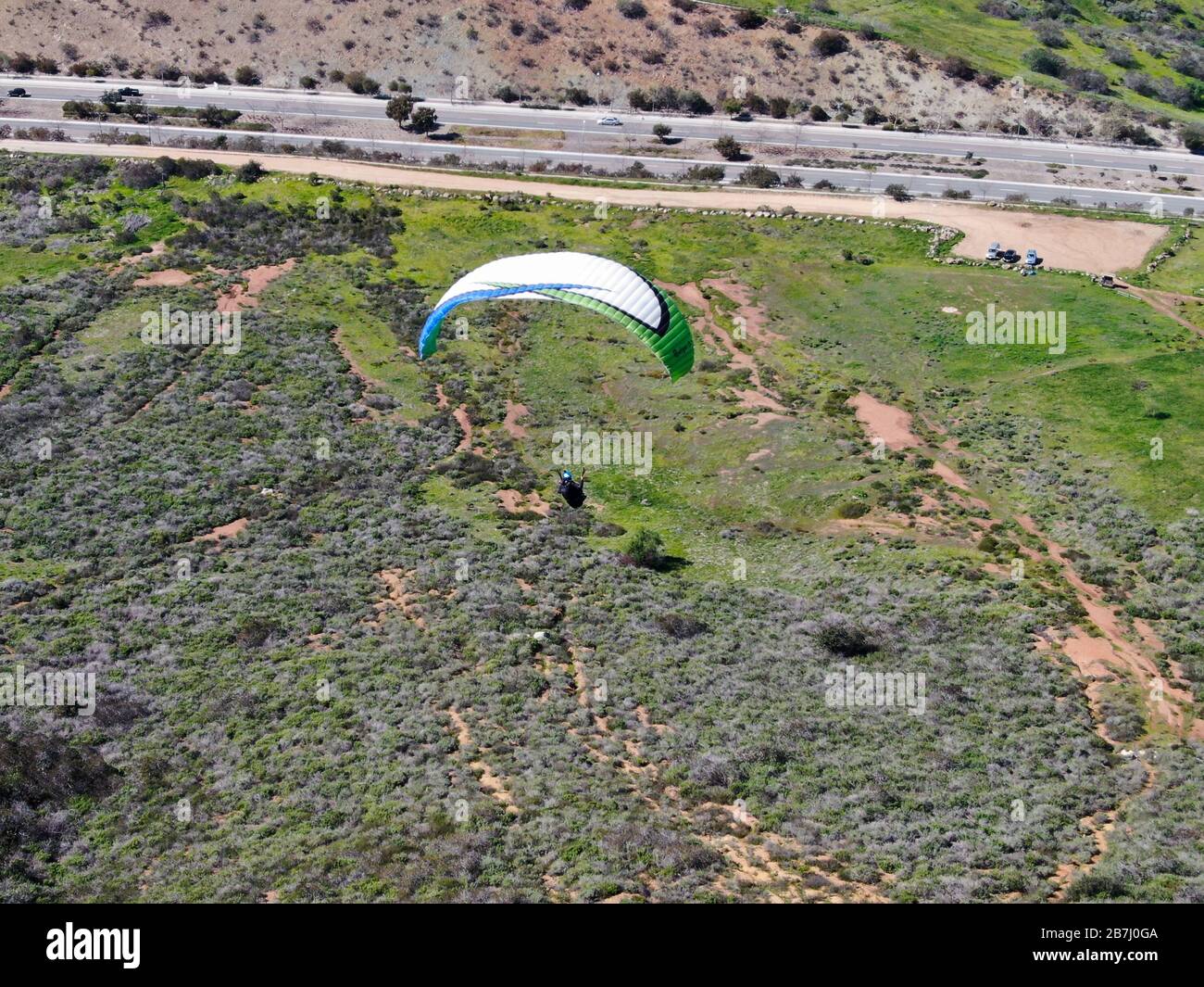 Para-glider over the top of the mountain during summer sunny day. Para-glider on the para-plane, strops -soaring flight moment flying over Black Mountain in San Diego, California. USA. February 22nd, 2020 Stock Photo
