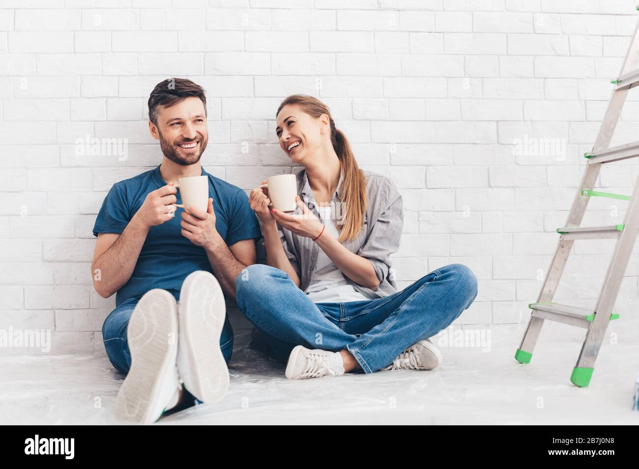 Young smiling couple drinking tea and coffee in new apartment Stock Photo