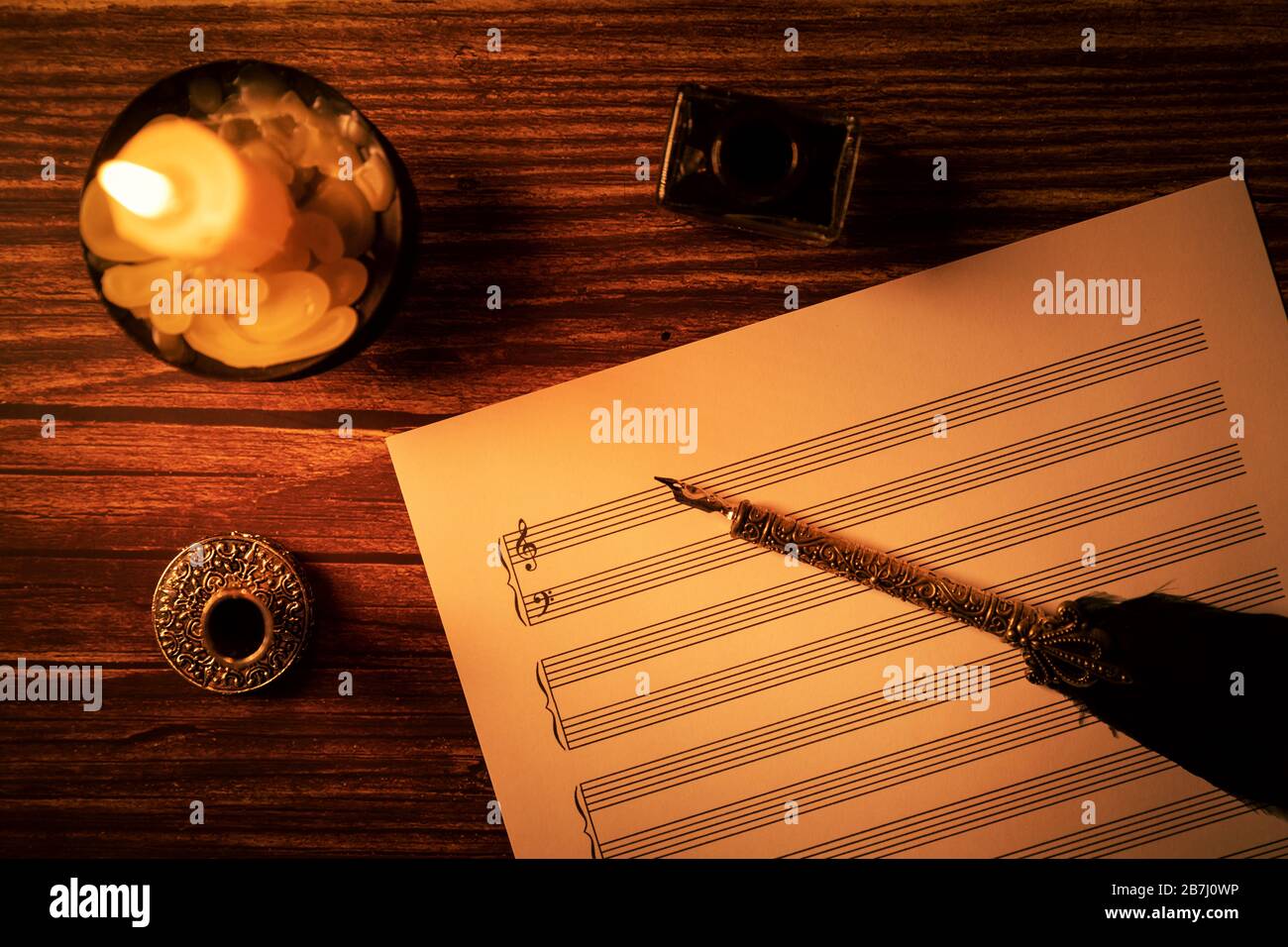 musical notes sheet with vintage feather quill pen in candlelight. top view Stock Photo