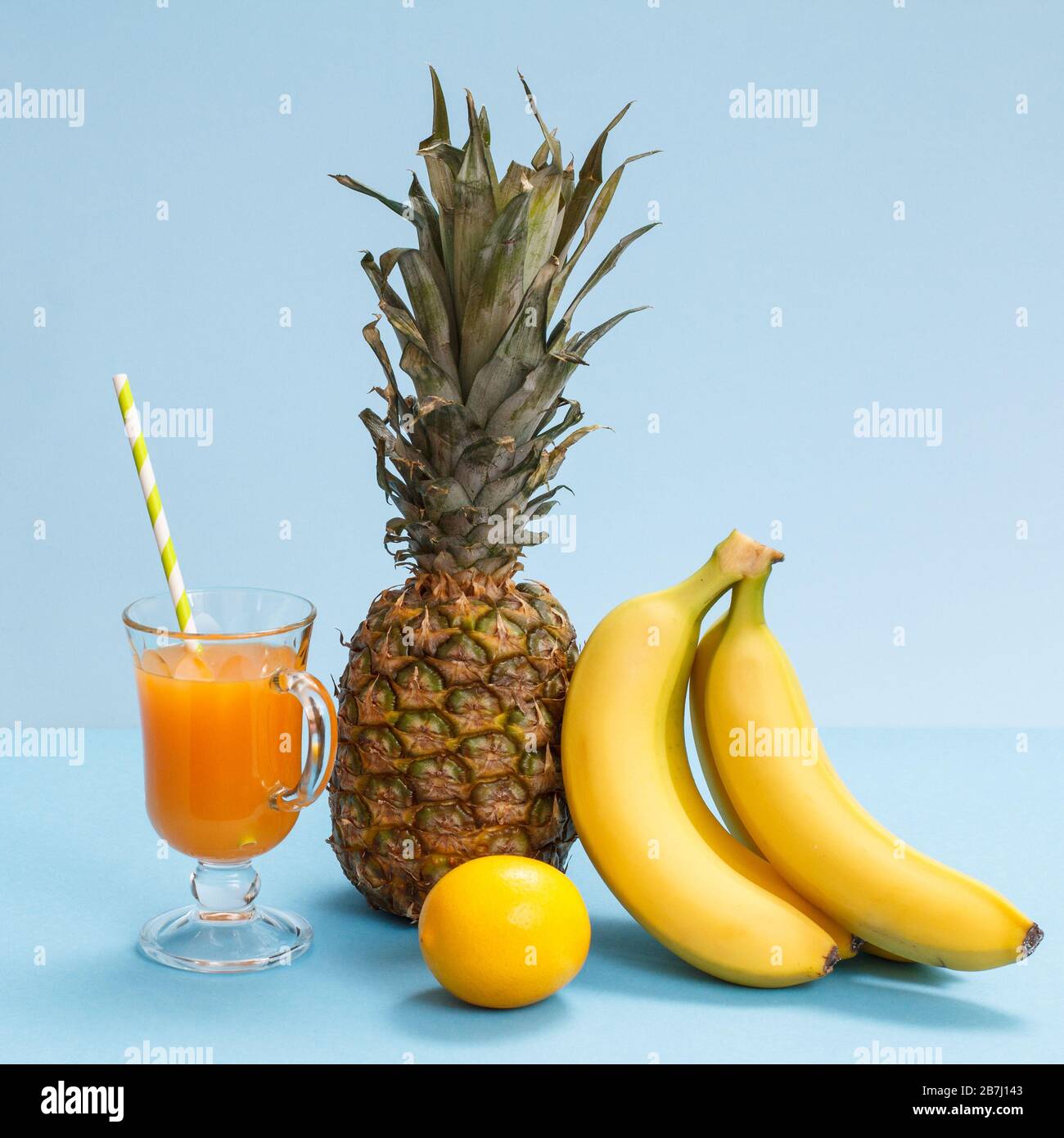 Glass of fruit juice, fresh pineapple, lemon and bananas on blue background  Stock Photo - Alamy