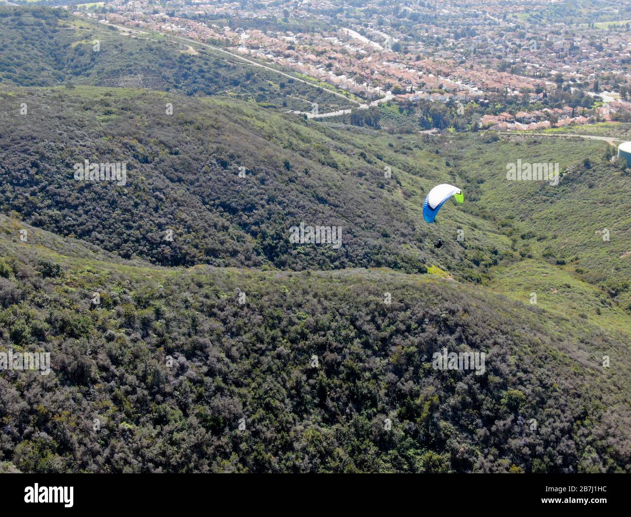 Para-glider over the top of the mountain during summer sunny day. Para-glider on the para-plane, strops -soaring flight moment flying over Black Mountain in San Diego, California. USA. February 22nd, 2020 Stock Photo