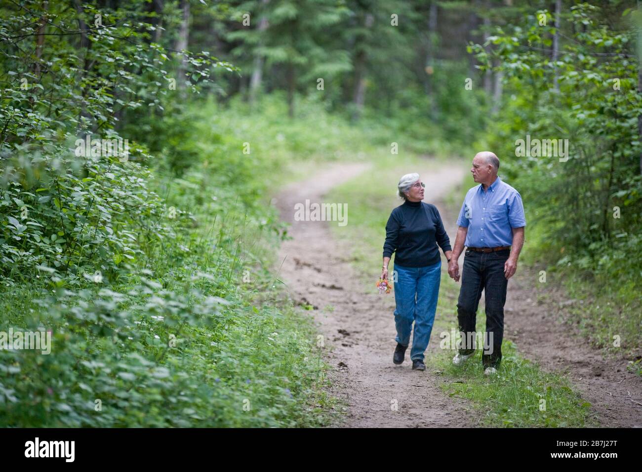 Mature couple walking a forest path Stock Photo - Alamy