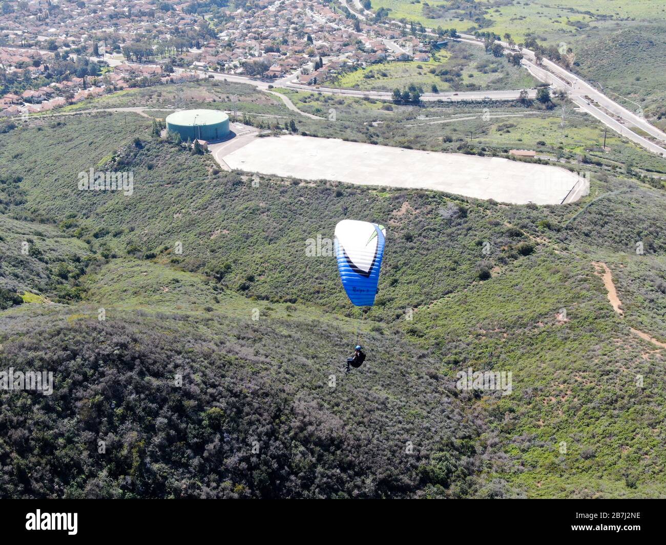 Para-glider over the top of the mountain during summer sunny day. Para-glider on the para-plane, strops -soaring flight moment flying over Black Mountain in San Diego, California. USA. February 22nd, 2020 Stock Photo