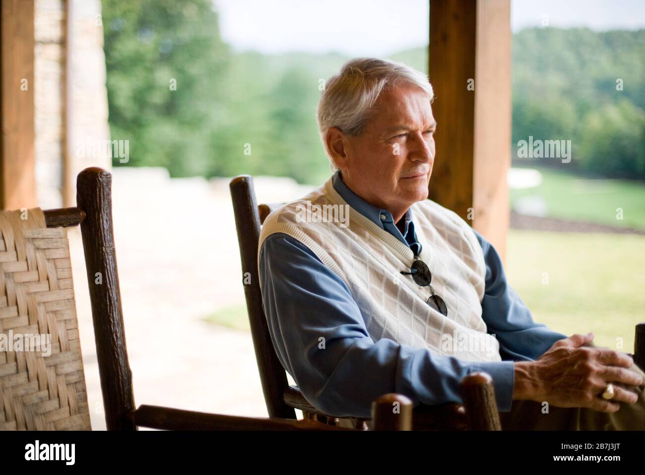 Older man sitting outdoors looking contemplative Stock Photo