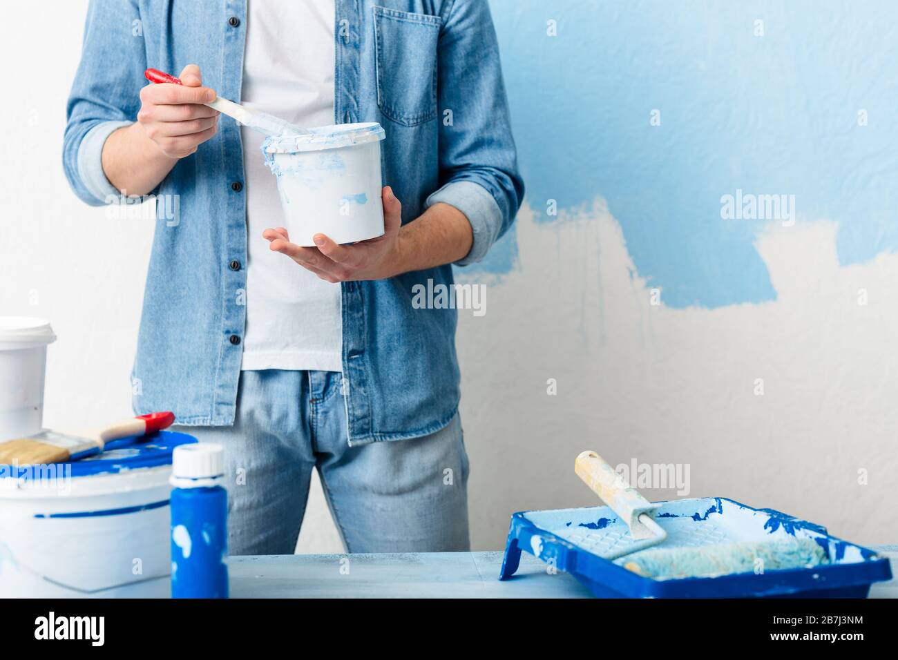 Homemade repairs concept. Guy mixes paint in bucket Stock Photo