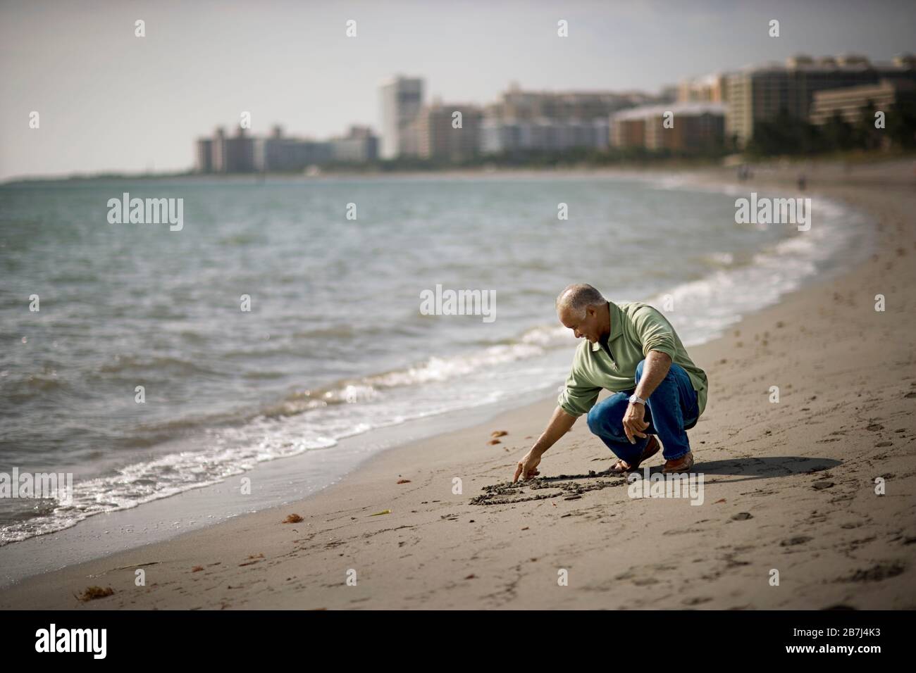 Mature adult man drawing in the sand on a beach Stock Photo - Alamy