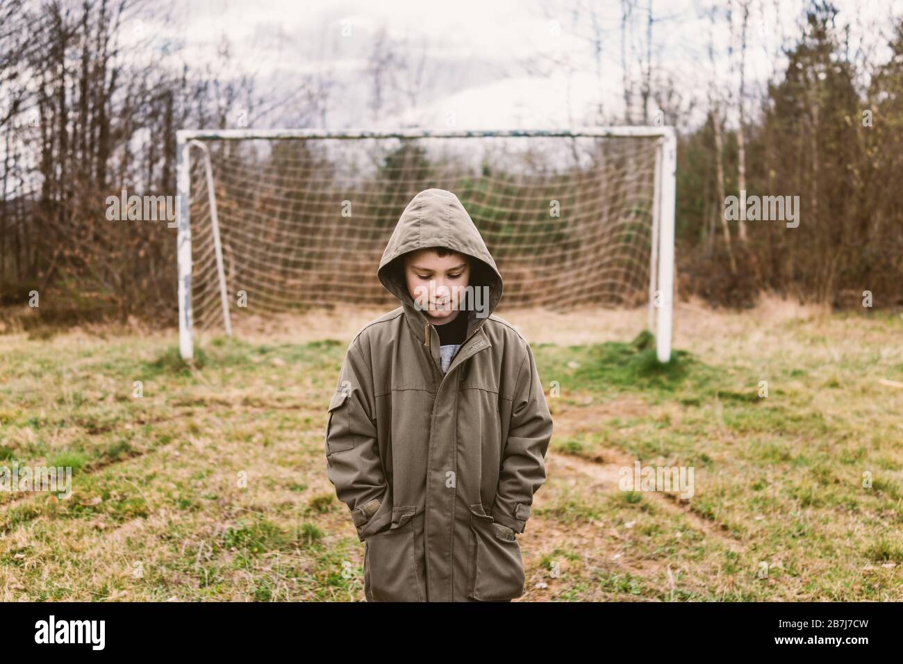 Boy standing on a deserted footbal field Stock Photo
