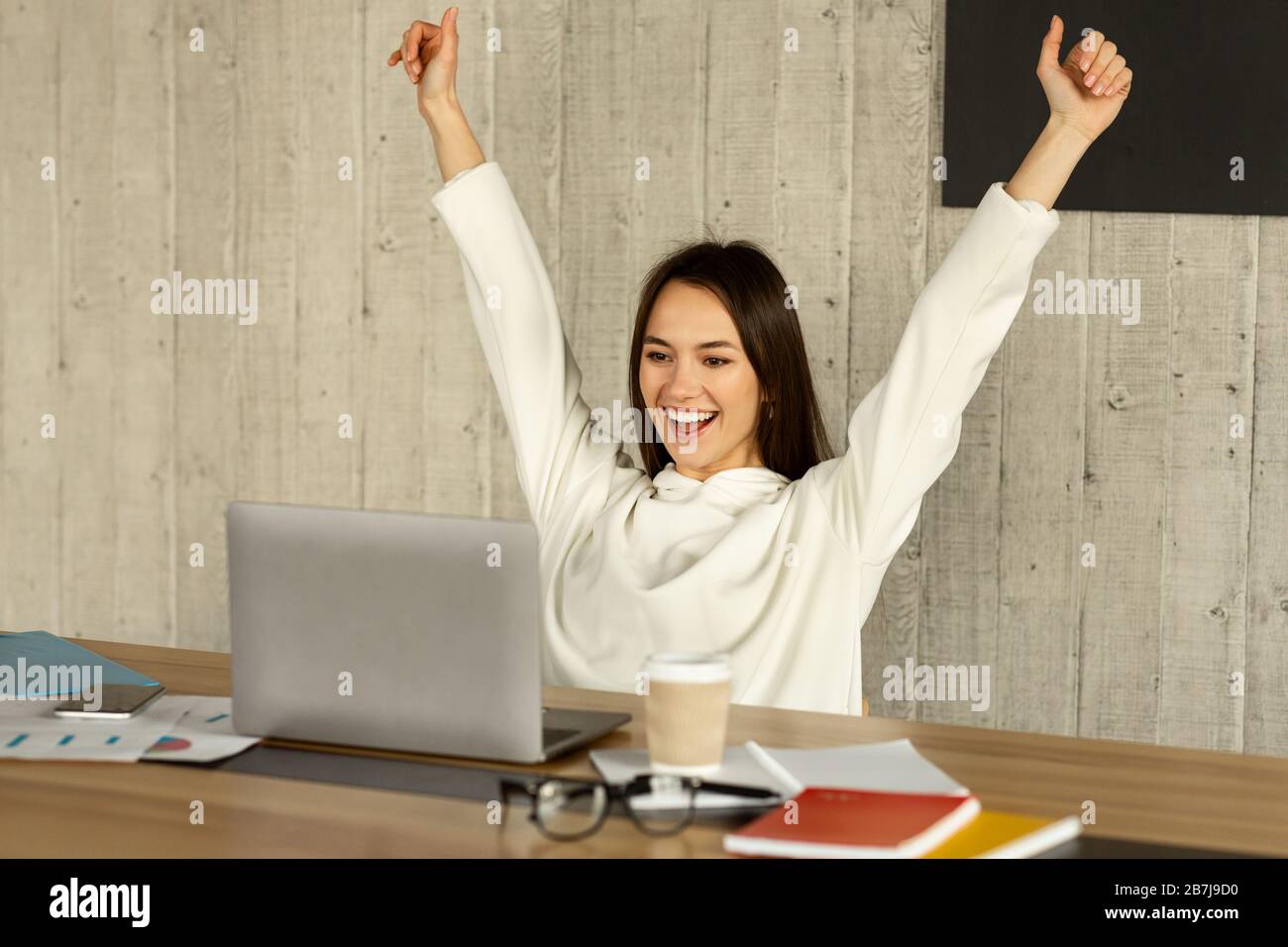Great day at work. Woman raises hands up Stock Photo