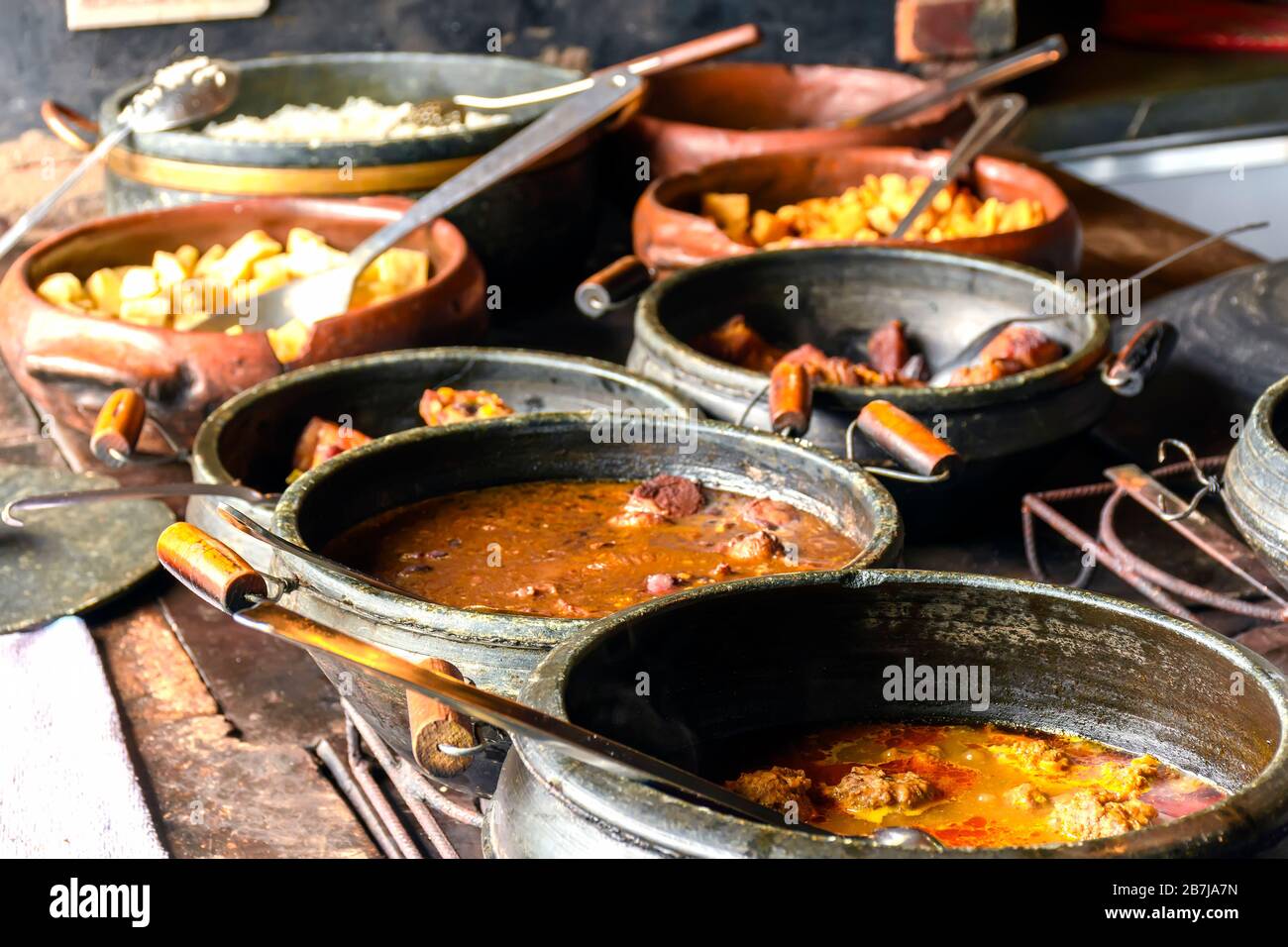 Typical Brazilian foods placed in clay pots and on a metal plate of a traditional wood stove Stock Photo