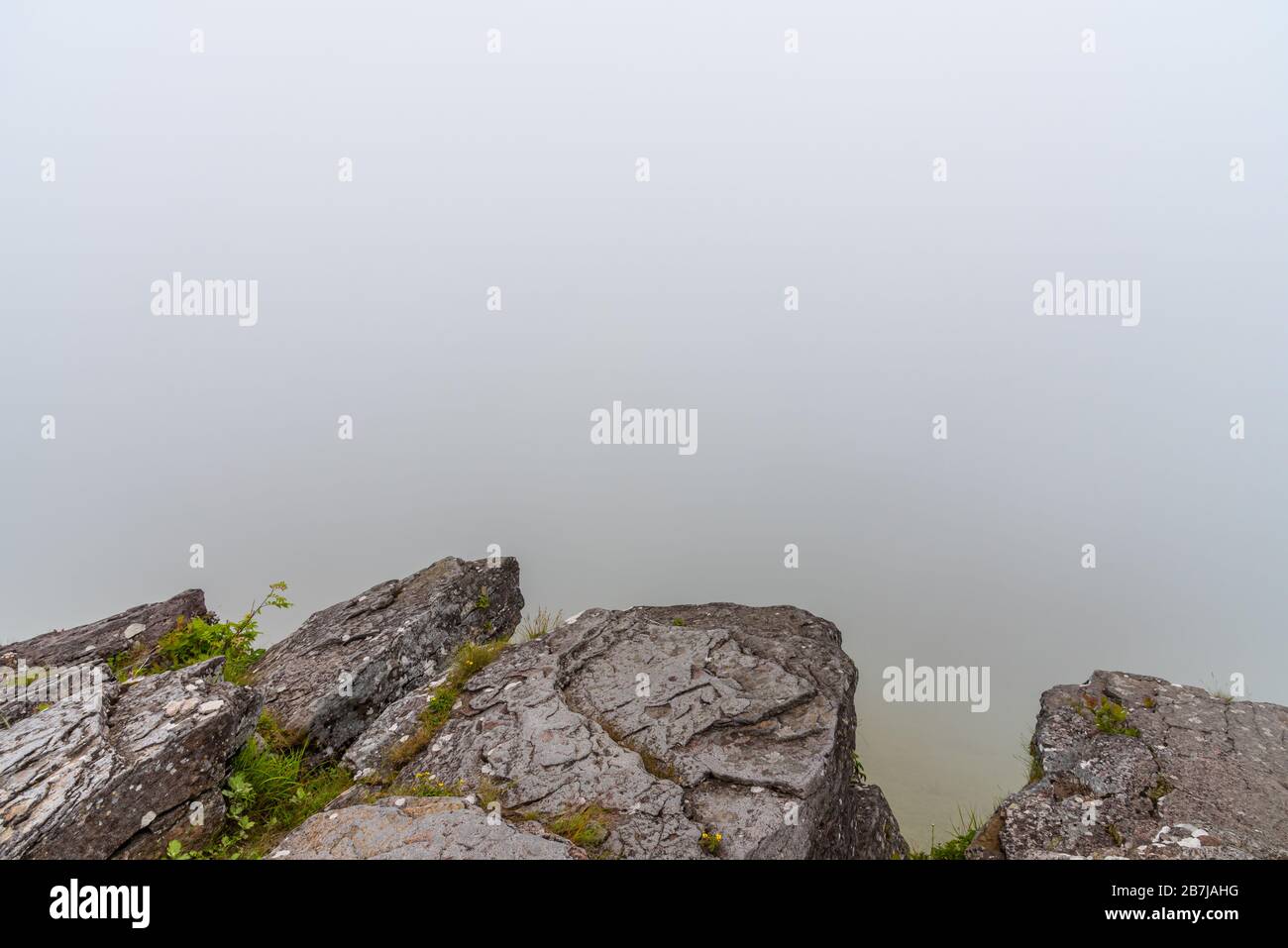 Rocks in the foreground and dense fog in the background Stock Photo