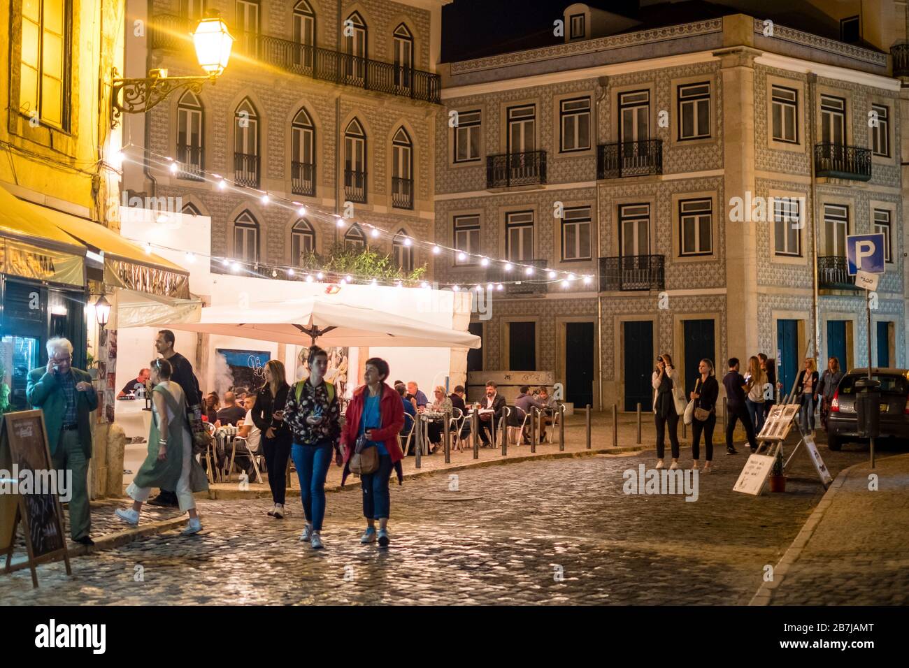 Tourists stroll cobblestone streets at night in the Alfama district, Lisbon, Portugal Stock Photo