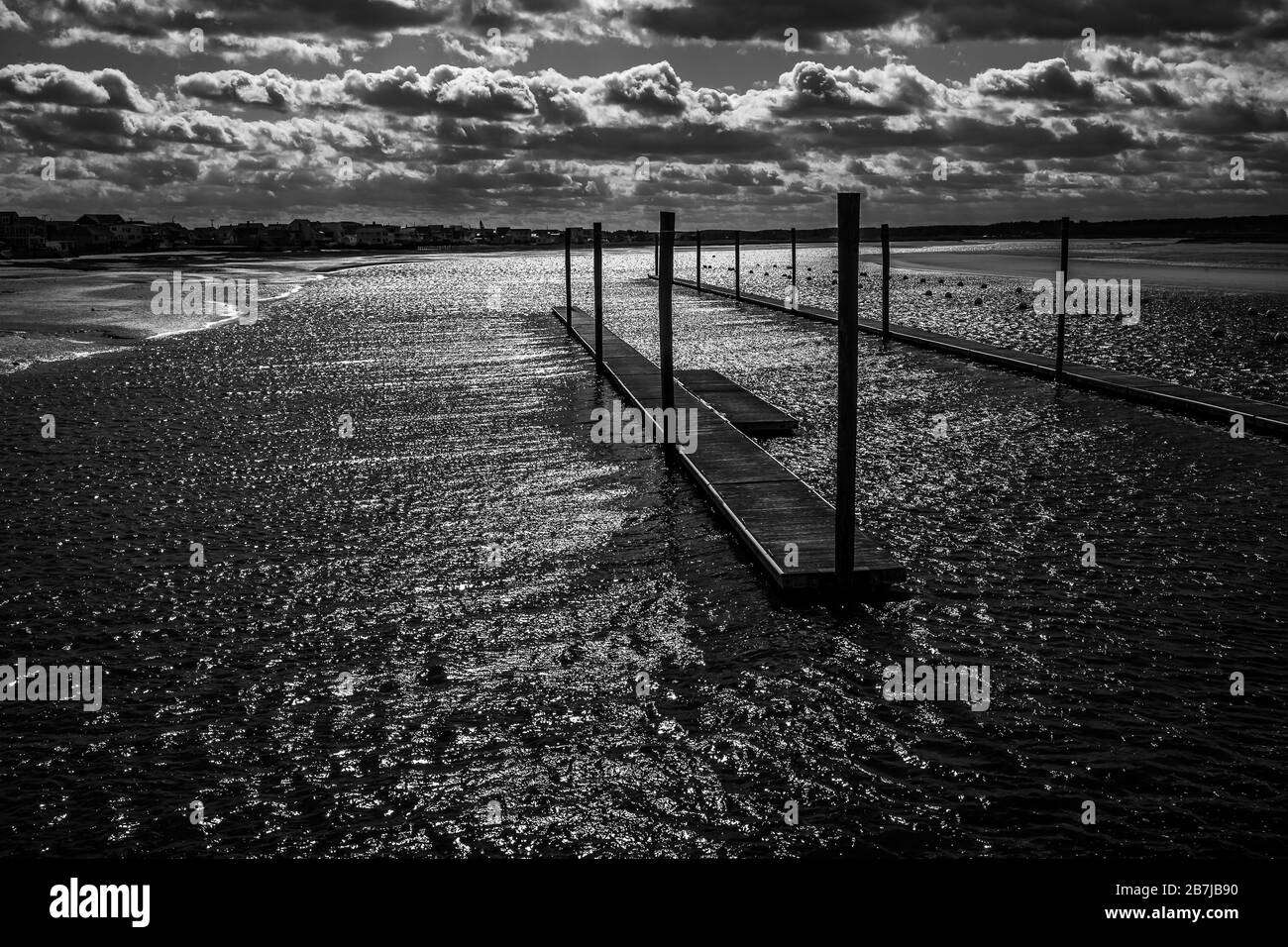 These empty docks, and moorings, take on a lonesome look as the wind blows across the harbor water on this very cold lonely cloudy winter morning.. Stock Photo