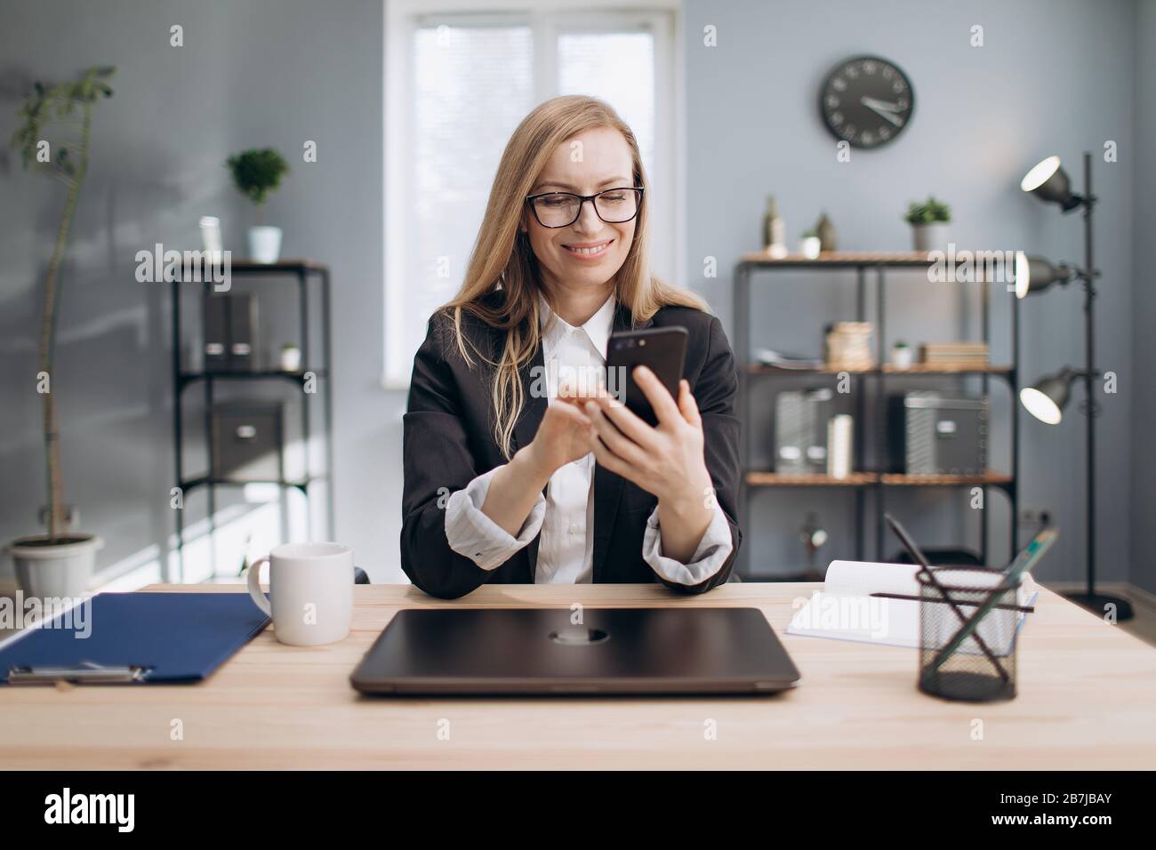 Cheerful lady using smartphone to solve business issues Stock Photo
