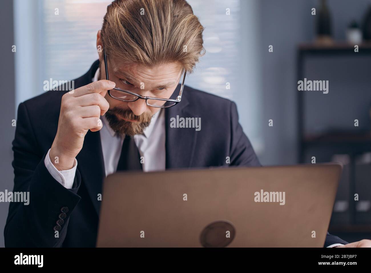A Confused businessman looking at computer screen Stock Photo