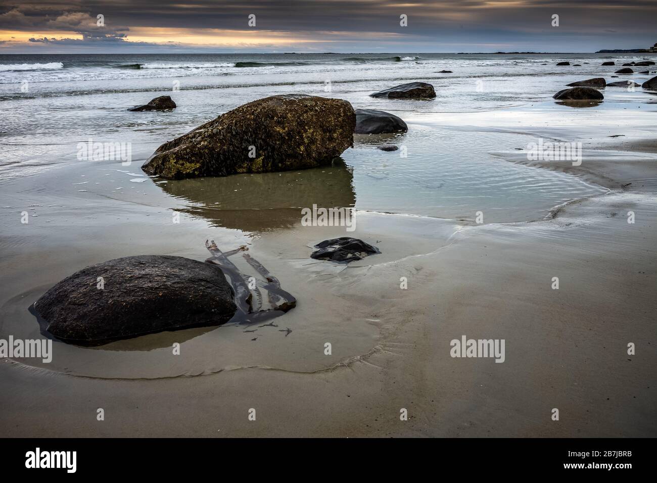 Cold winter morning light breaks on this beach at low tide, showing all the rocks alone this lonely sandy coastline. Stock Photo