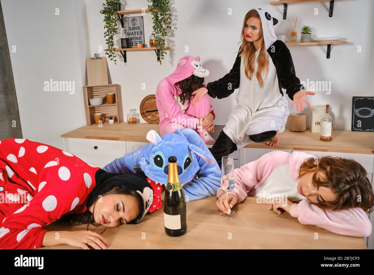 Girls dressed in plush pajamas in form of cartoons characters enjoying hen-party. Some of them got drunk, fell asleep on kitchen worktops. Close-up Stock Photo