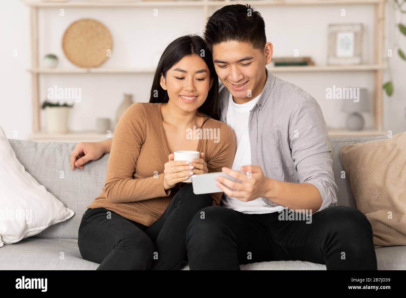 Korean couple resting at home, using phone Stock Photo