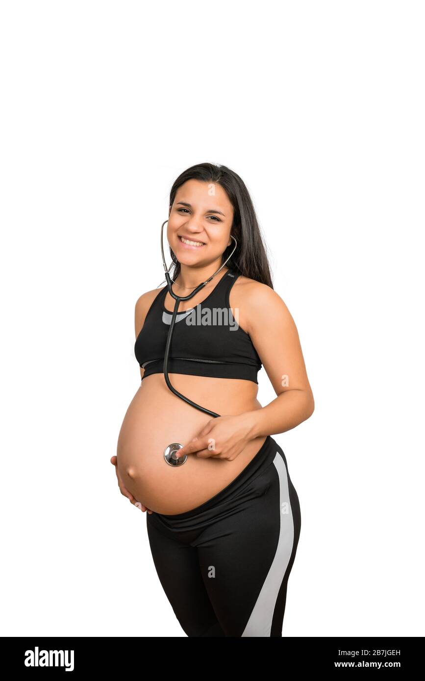 Close-up of pregnant woman with stethoscope on belly listening to the baby. Pregnancy, lifestyle and motherhood concept. Stock Photo