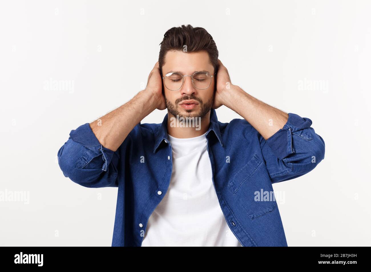 young man covering his ears, closing his eyes, isolated on white background. Hear no evil concept. Emotions facial expressions and communication sign Stock Photo
