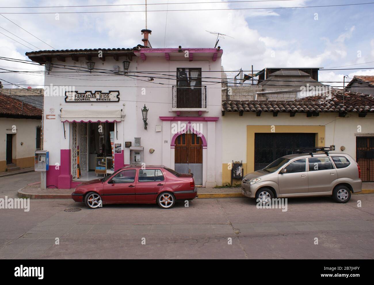 Colourful houses with matching cars on a street in San Christóbal de las Casas, Mexico Stock Photo