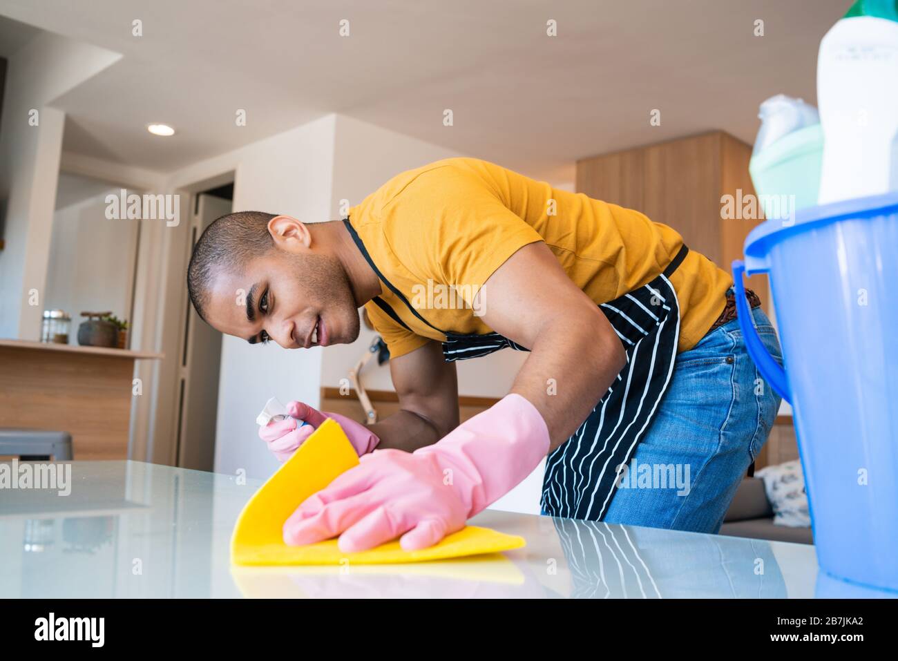 Close up of young latin man cleaning stains off the table at home. Housekeeping and cleaning