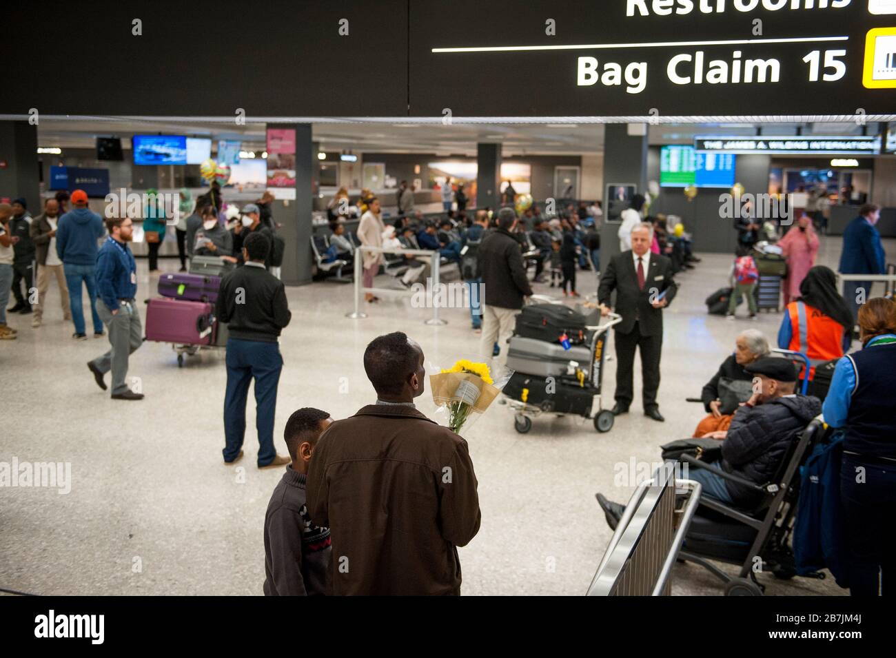 A man waits with a bouquet of flowers as passengers arrive at the