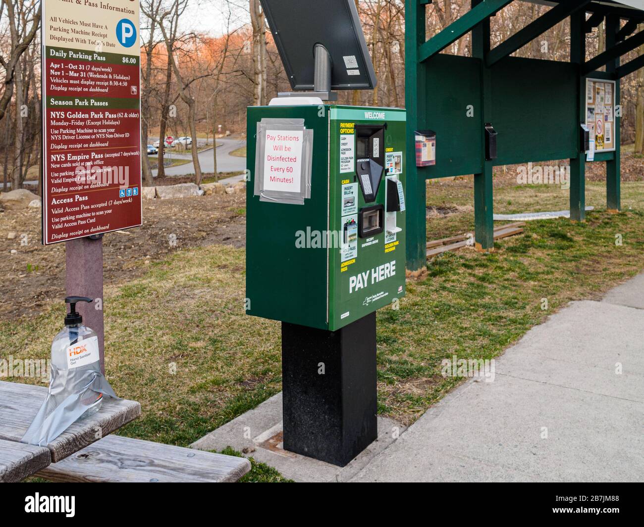 Westchester County, New York, 15 March, 2020: A bottle of hand sanitizer is secured by duck tape in the parking lot of Rockefeller State Park Preserve for hikers. Sign that parking meter is disinfected hourly over coronavirus fears. Westchester County currently has the highest incidence of COVID-19 in the state.  Due to shortages, there have been reports of people stealing hand sanitizer from offices and other public spaces. Stock Photo
