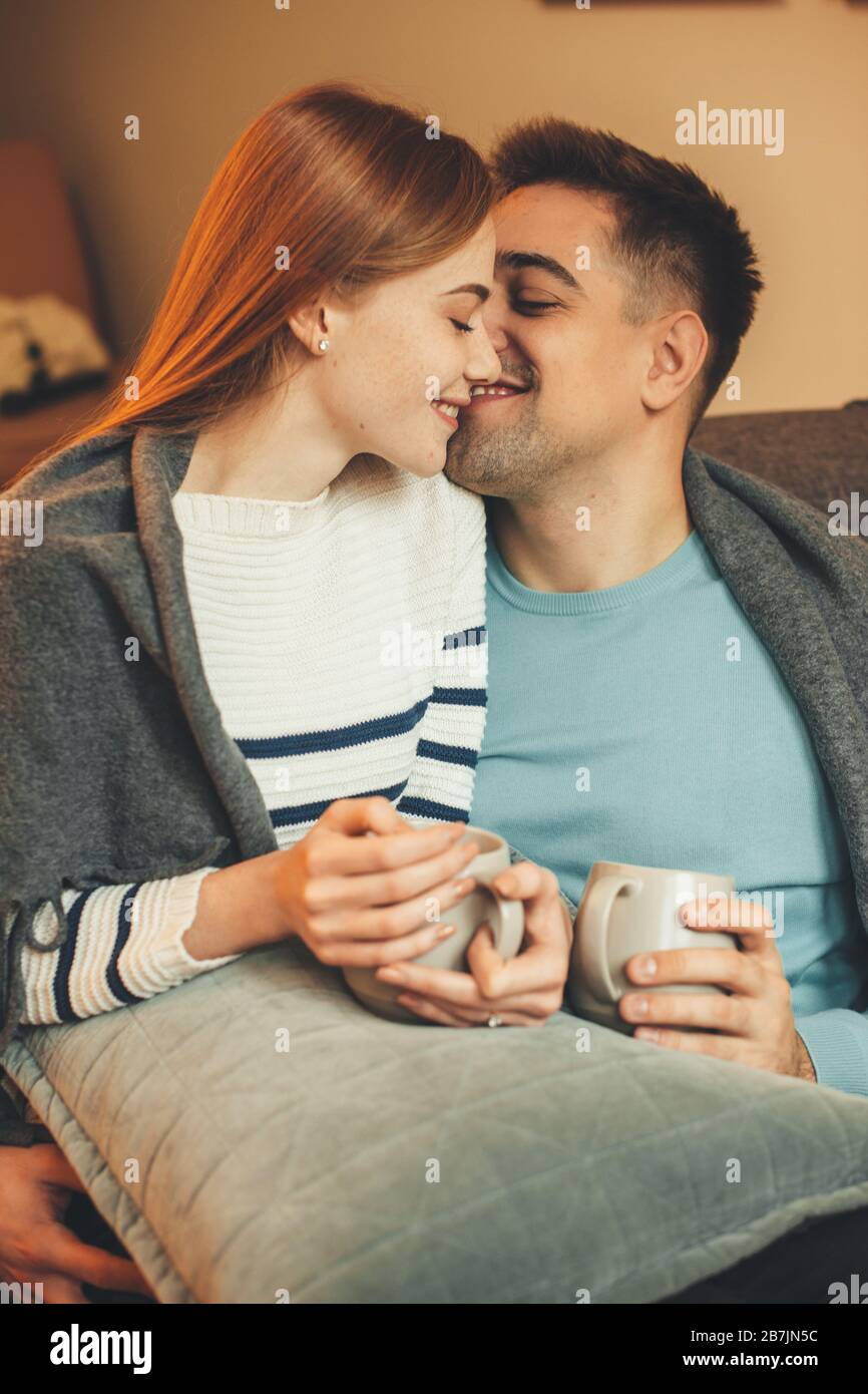 Lovely caucasian couple having a coffee break while sitting on the sofa