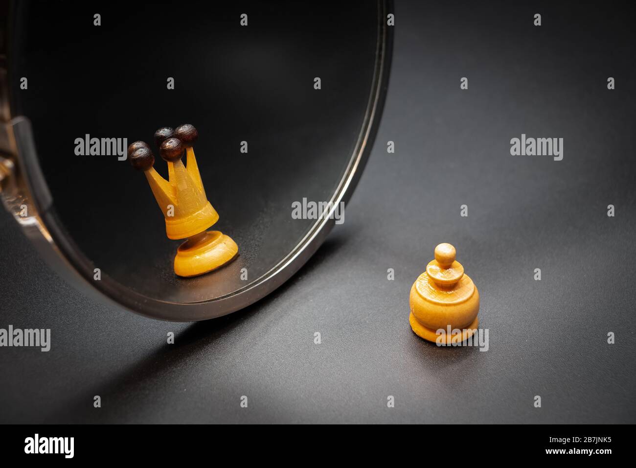 Pawn looking in the mirror and seeing himself like a king with dark background. Psychological concept Stock Photo