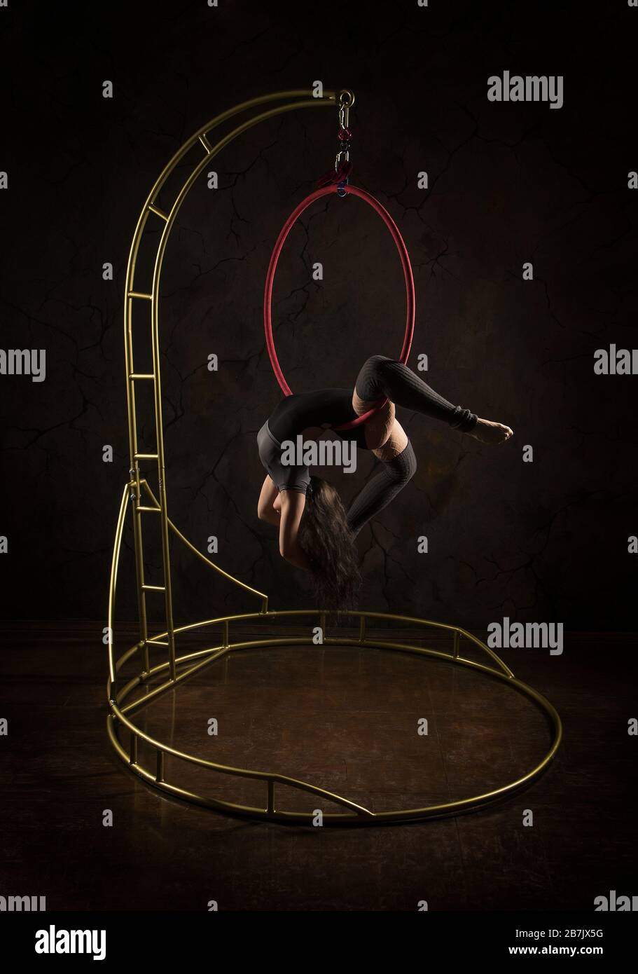 Gorgeous woman, aerial acrobat, in a dark suit performs acrobatic ...