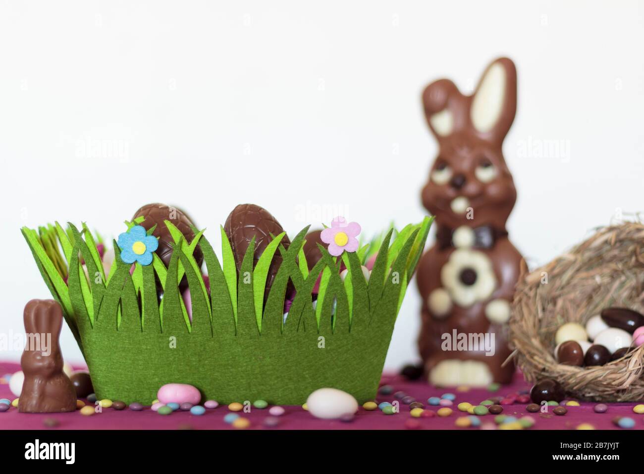 Easter basket with chocolate eggs, chocolate bunny, nest with almonds