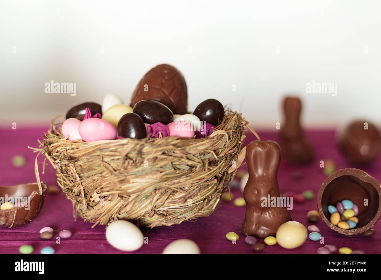 Nest with chocolate eggs, chocolate bunny and sweets on easter table Stock Photo