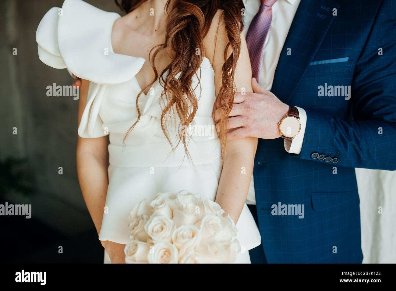 Stylish wedding picture. The groom in a blue suit gently embraces the bride in a white stylish dress made of stiff fabric. Puffy wedding dress sleeve, Stock Photo