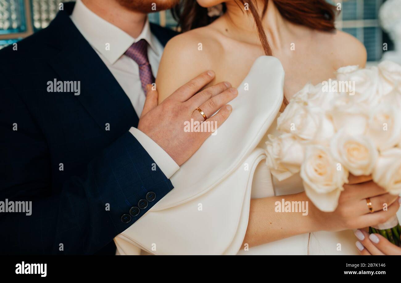 Stylish wedding picture. The groom in a blue suit gently embraces the bride in a white stylish dress made of stiff fabric. Puffy wedding dress sleeve, Stock Photo