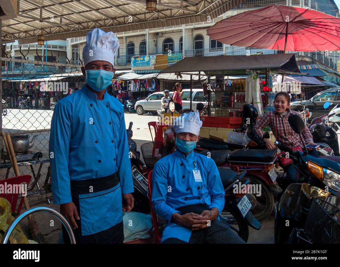 Battambang, Cambodia, Asia: two chefs with masks and a smiling girl during a work break Stock Photo