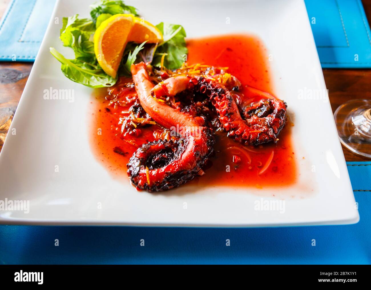 Plate of grilled teriyake octopus served with agreen salad and orange slice garnish in a restaurant in Hanga Roa, Easter Island (Rapa Nui), Chile Stock Photo