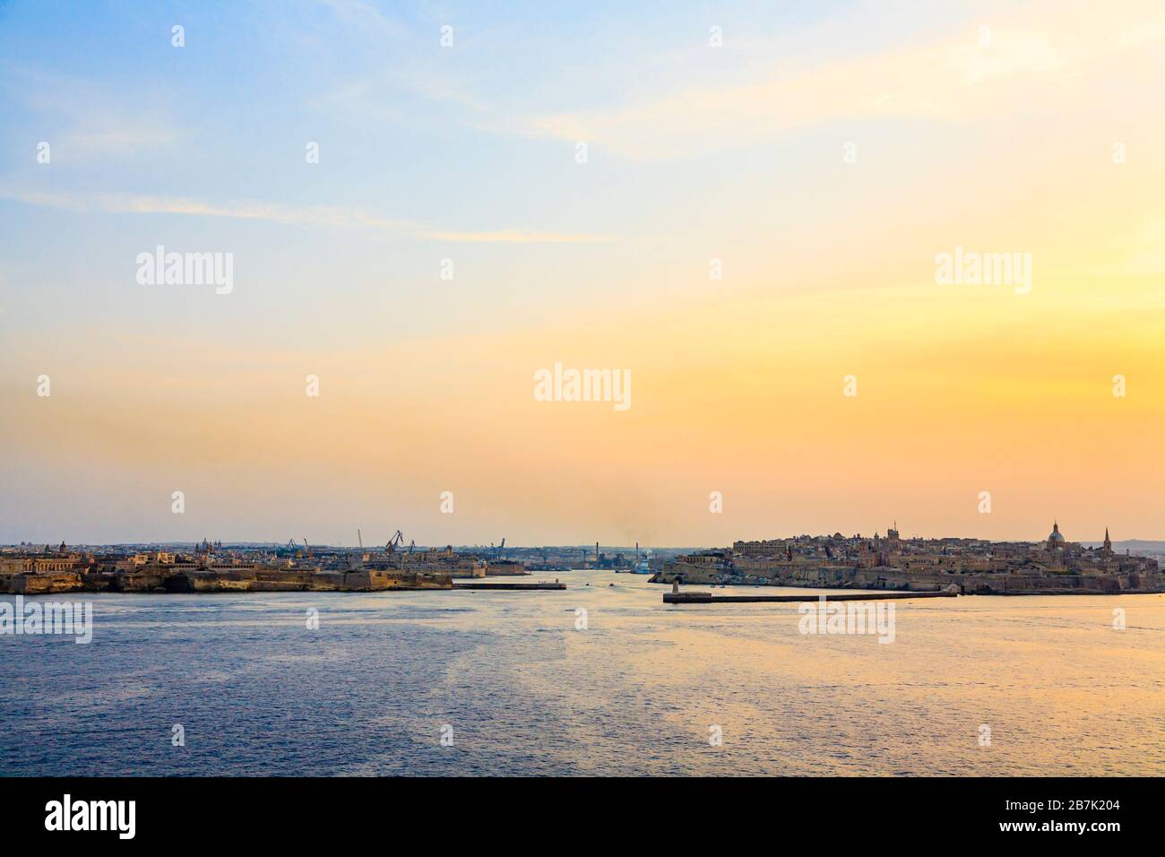 Iconic panoramic view of the entrance to Grand Harbour and city skyline in the evening at sunset, Valletta, capital city of Malta Stock Photo