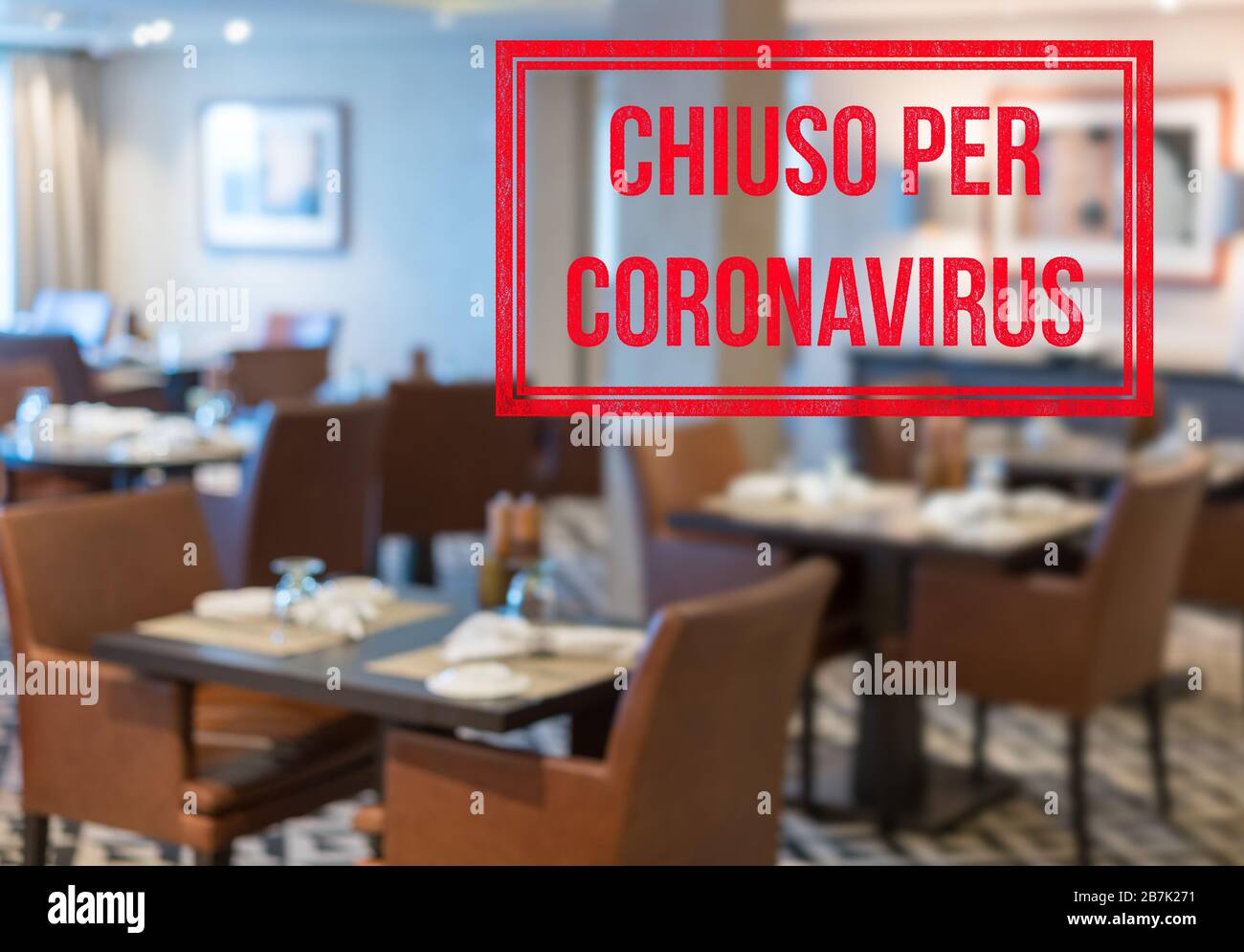 Defocused view of interior of an upmarket restaurant empty and closed with Italian notice saying Closed due to Coronavirus Stock Photo