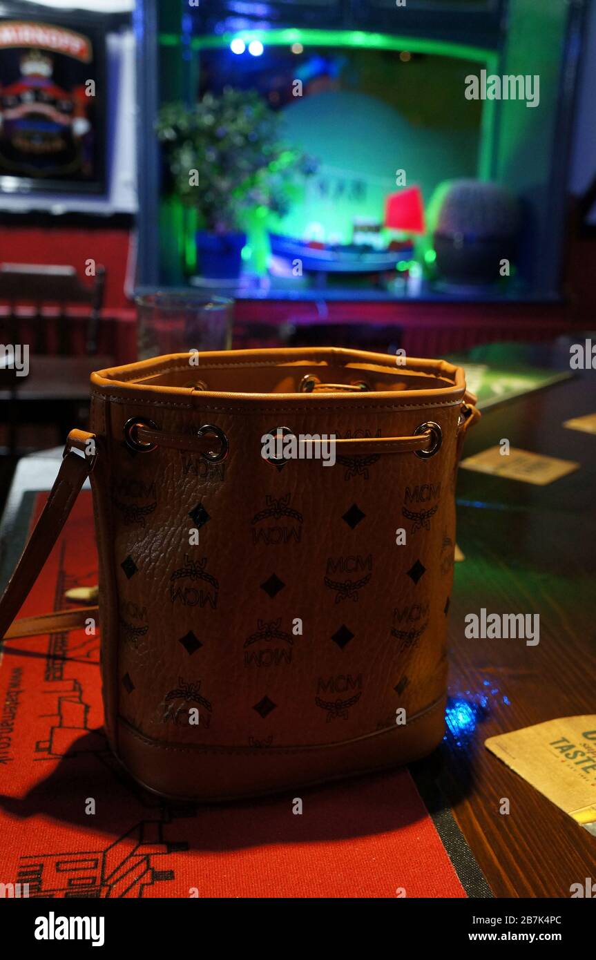 Leather handbag at the bar in a UK pub with green lit window in background Stock Photo